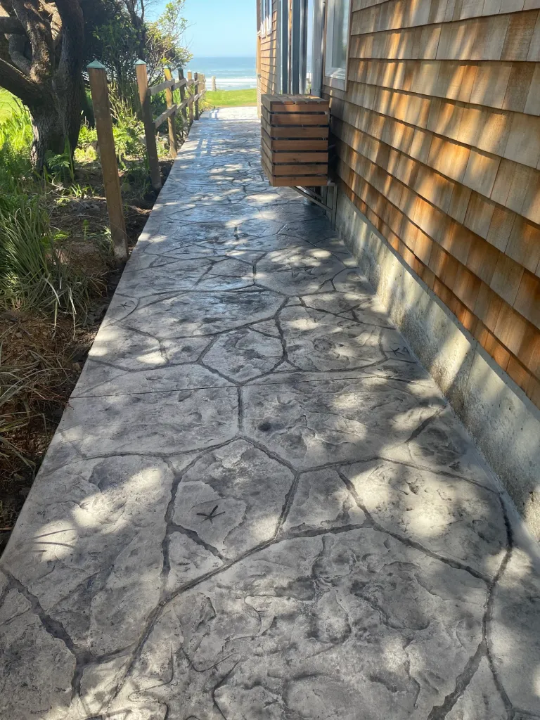 Custom stamped concrete in Leawood KS showcasing natural stone texture along coastal home walkway.